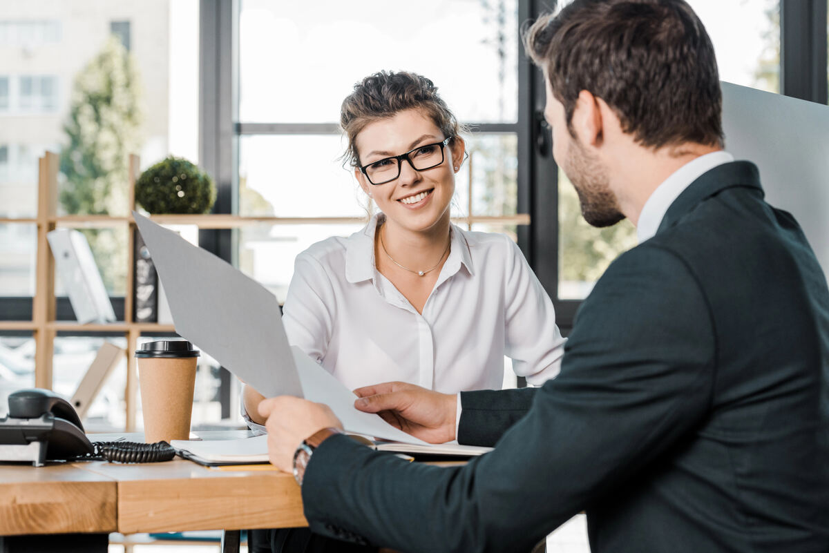 Client consultation: A male lawyer seated across from a female client at a meeting table, reviewing a printed document.