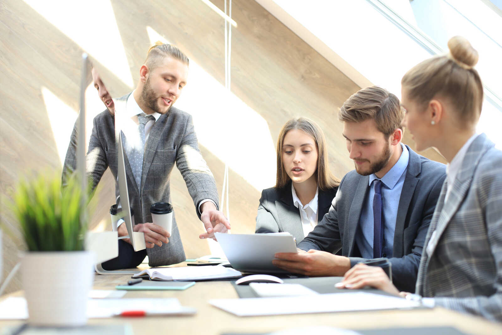 A group of well-dressed young lawyers looking at and discussing various proposals.