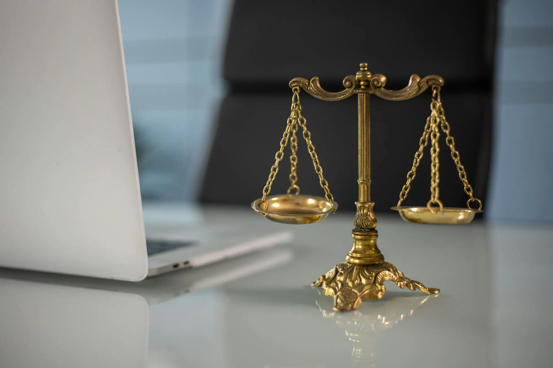 The scales of justice on a desk beside a laptop