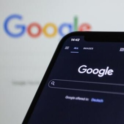 Mobile phone and laptop screen both showing Google homepage