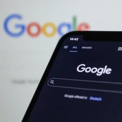 Mobile phone and laptop screen both showing Google homepage