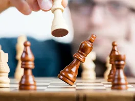 A dramatic image of a queen knocking over a king on a chessboard, symbolizing a dominant victory
