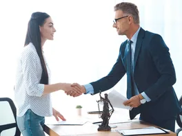 Side view of professional lawyer and young female client shaking hands.
