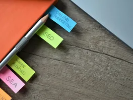 Close-up of a notebook with colourful tabs with various online marketing terms written on them