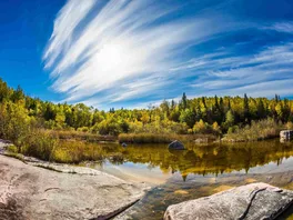 A bright sunny day in Old Pinawa Dam Park, with the Winnipeg River in the foreground.