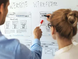 A male and a female web designer working together to mock up a new law firm website design on a whiteboard.