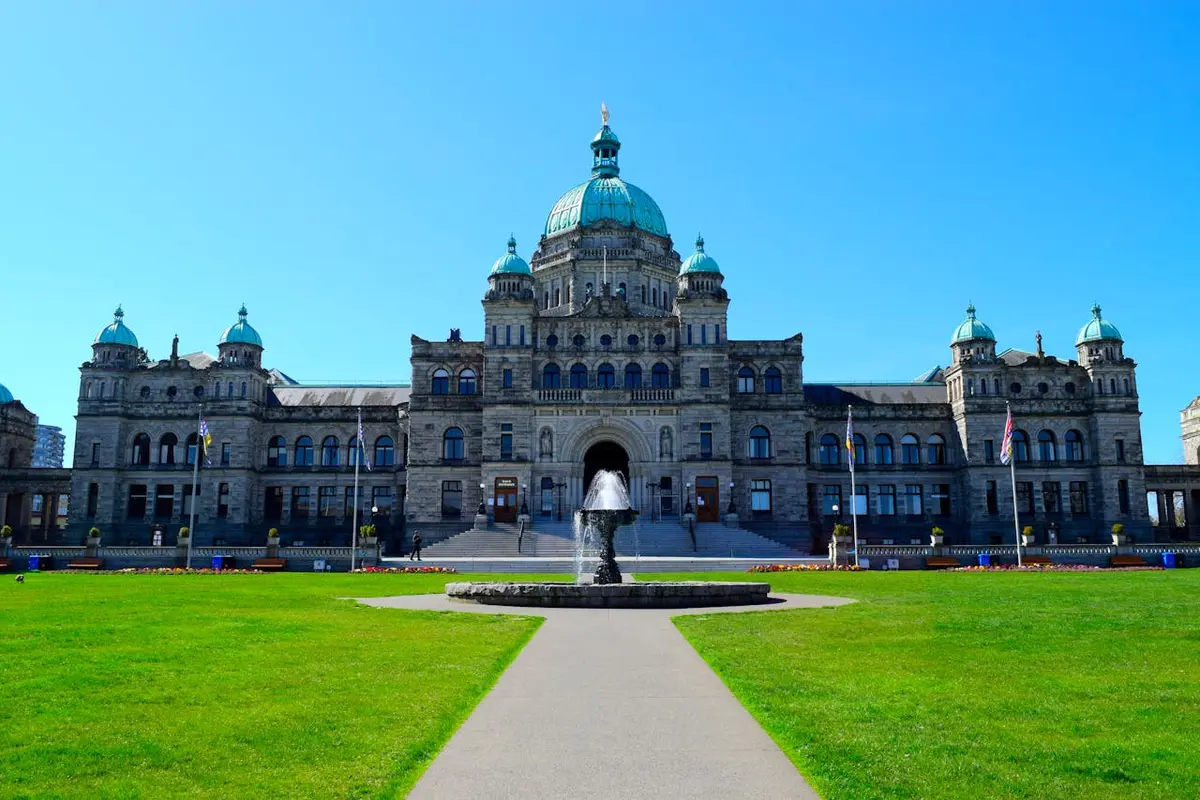 The main block British Columbia parliament buildings stands majestically over a perfectly green lawn in Victoria, British Columbia